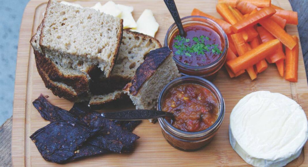 Local preserves on a cutting board with pickles and bread