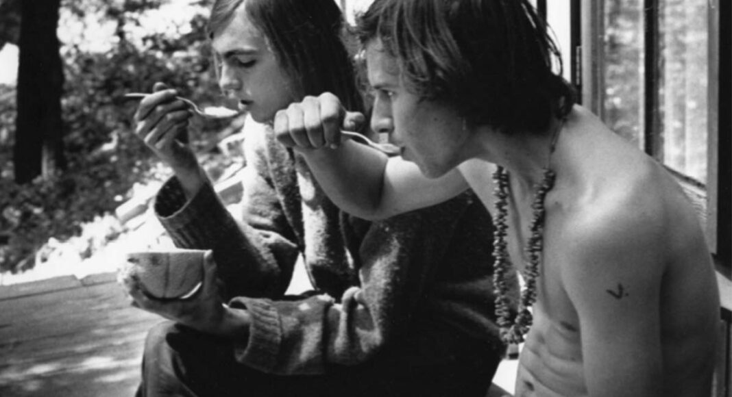 photograph of two young men eating soup on a porch