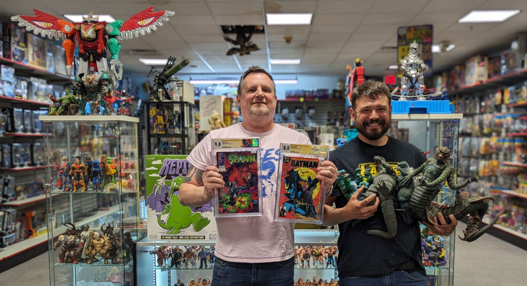 Two men holding up comics at toys in a collectibles shop