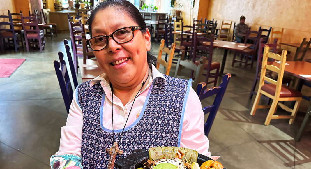 Woman holding a dish served in a round stone dish known as a molcajete