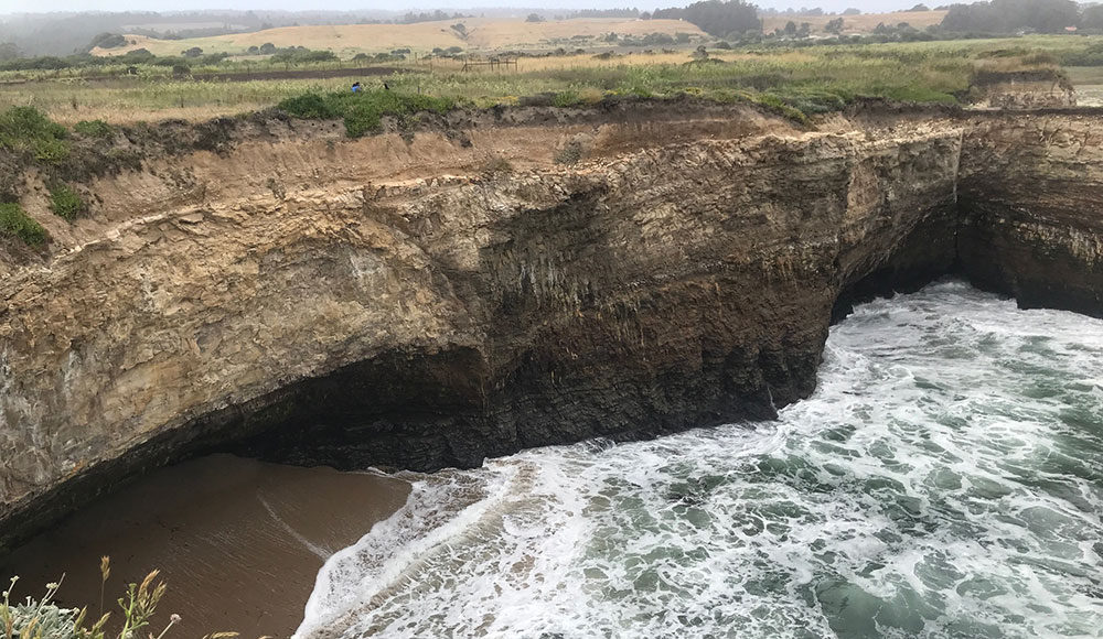 Scenic cliffs above an ocean cove with waves coming in