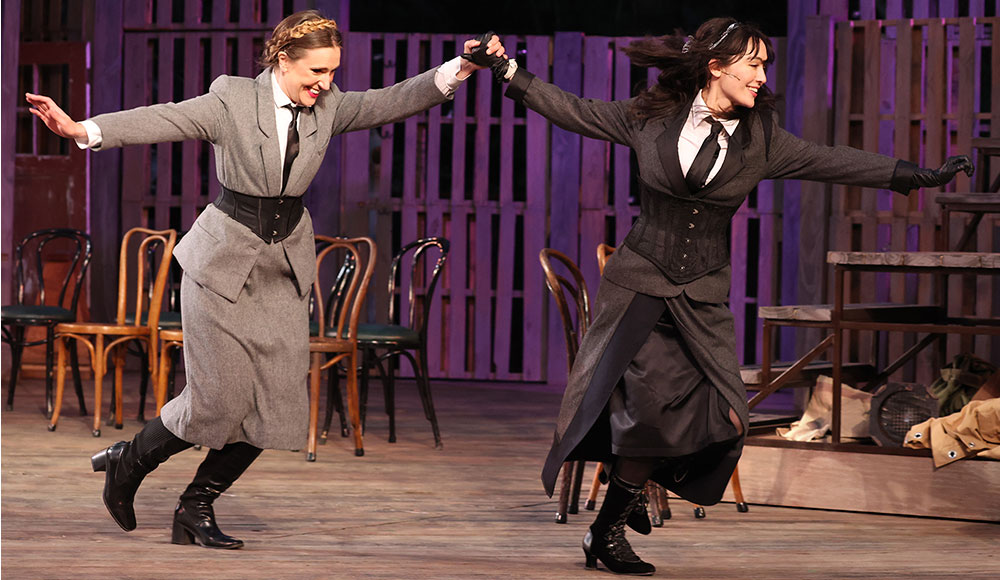 Two women in period costumes on stage