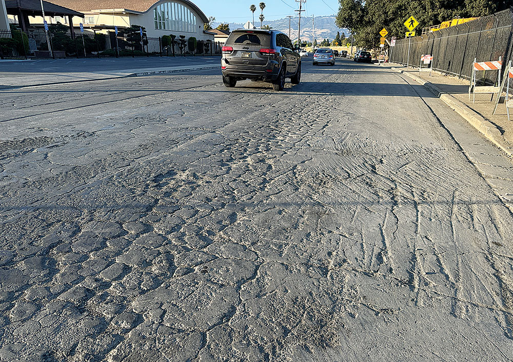 car driving down a road with lots of cracks and potholes