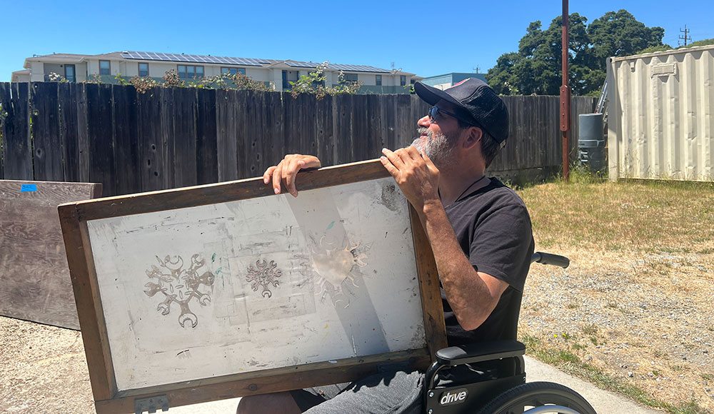 Man holding a large painting on his lap