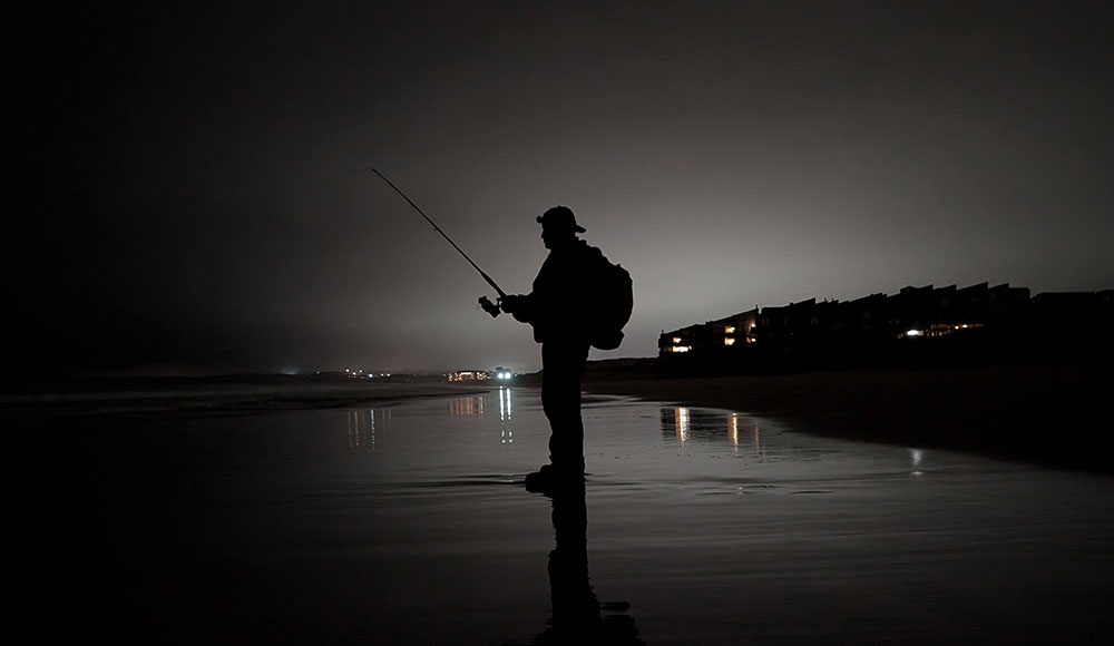 Silhouette of a fisherman on a lonely beach at night