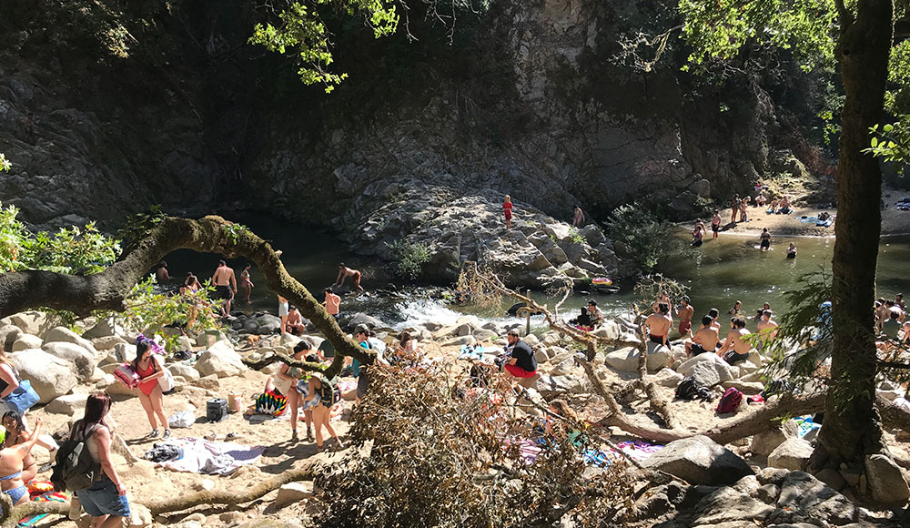 People walking down a path to a river pool
