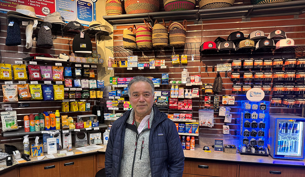 Man at a counter with a bunch of retail items behind him
