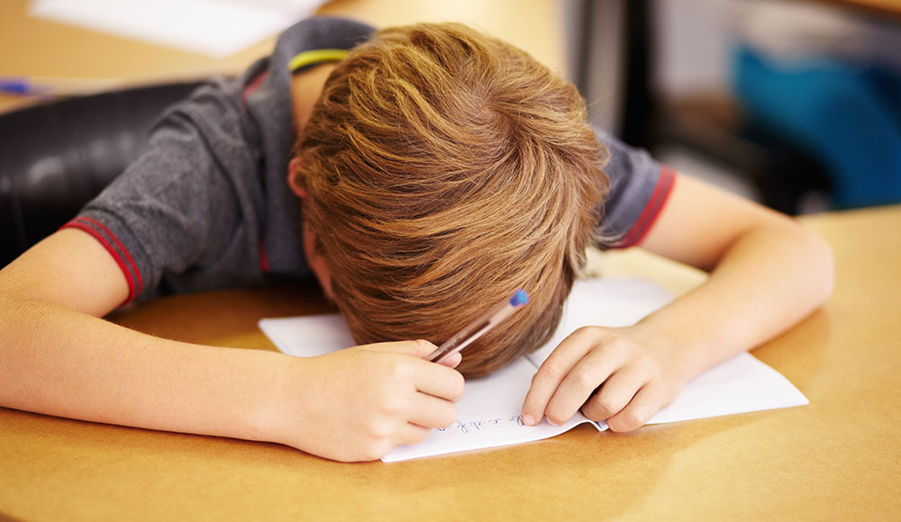 Child leaning face down on a desk