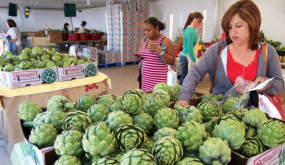 Woman picking artichokes up from a produce bin