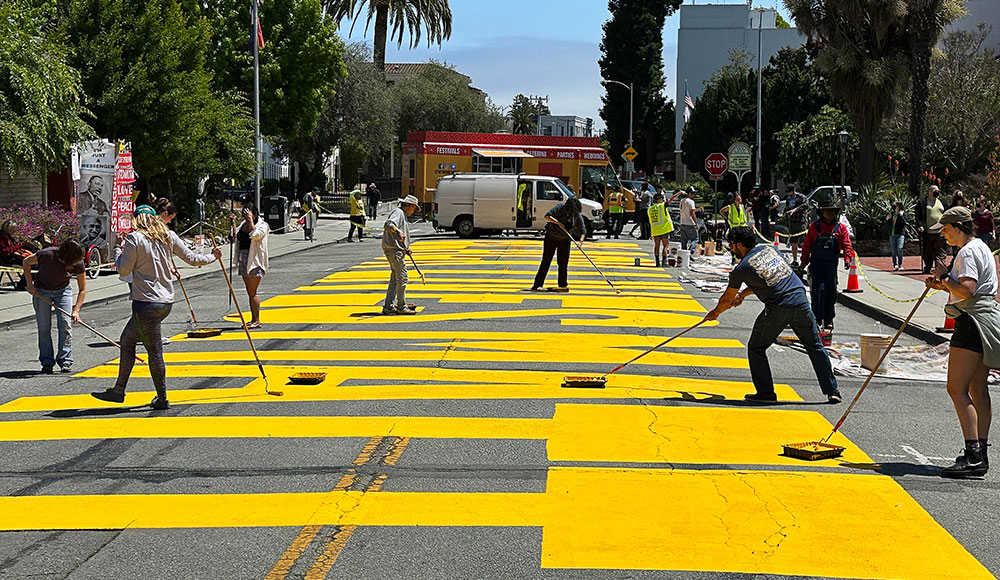 People applying paint to giant letters on a city street
