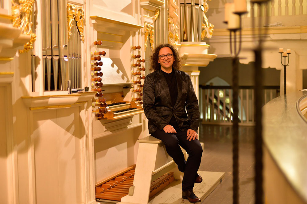 Jörg Reddin poses with a pipe grgan in a church.
