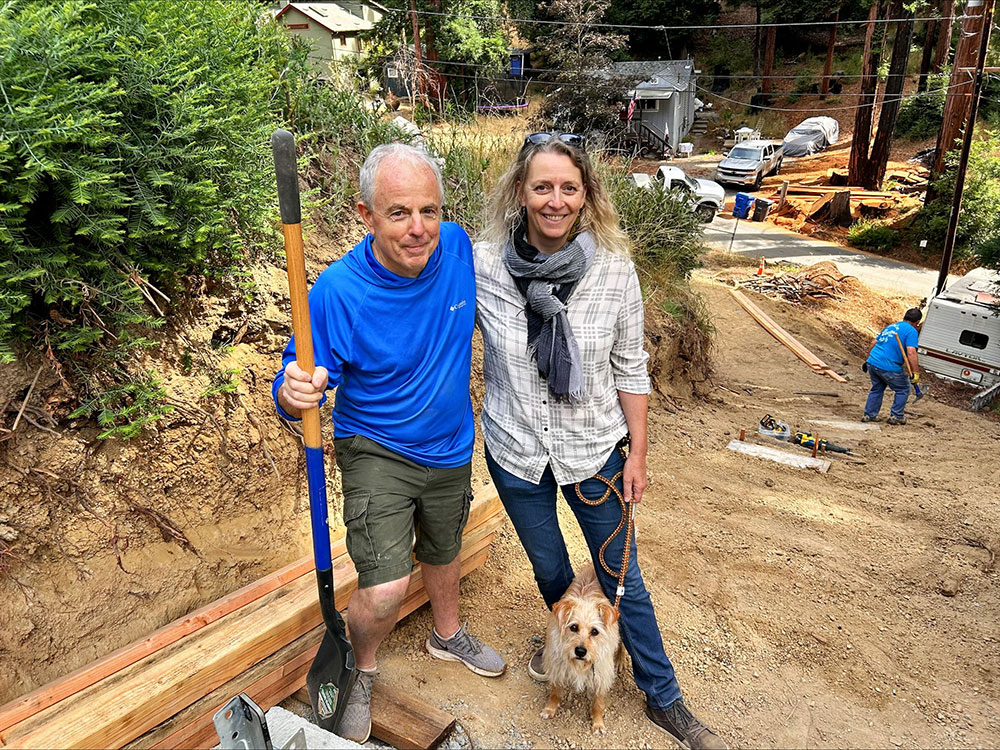 Two people posing at a construction site on a lot in the forest