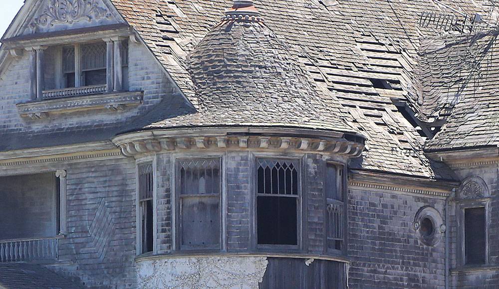 Closeup of the upper story of a dilapidated Victorian home