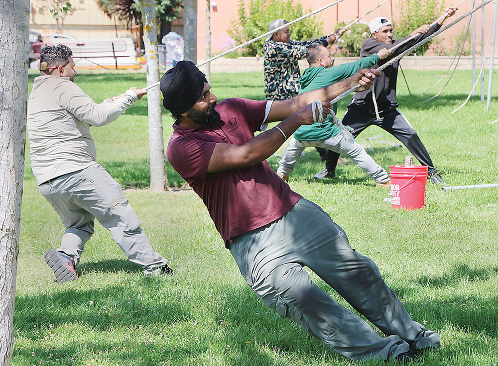 Five men tug on ropes as they erect a tent