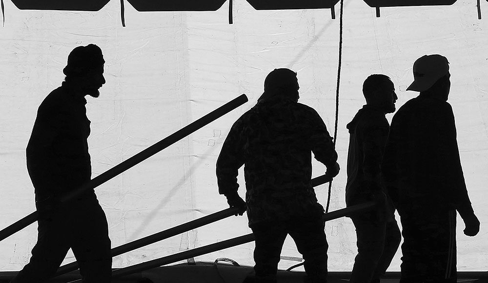 Silhouetted figures behind the wall of a tent