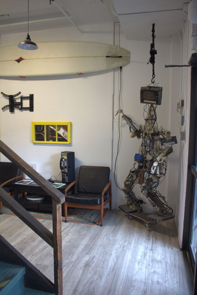 Sitting area by a staircase with a sculpture made out of junk in the corner