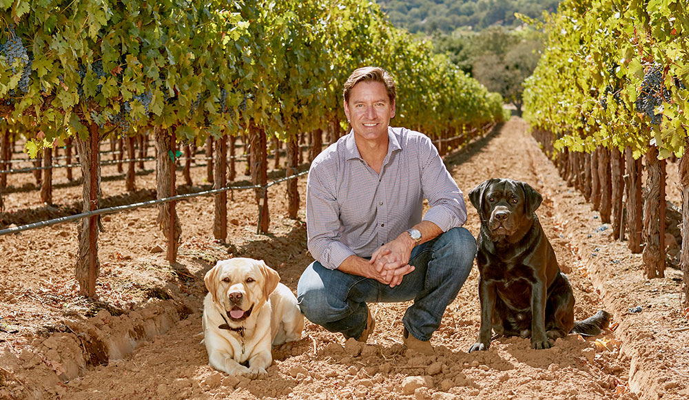man and dog and grape vines