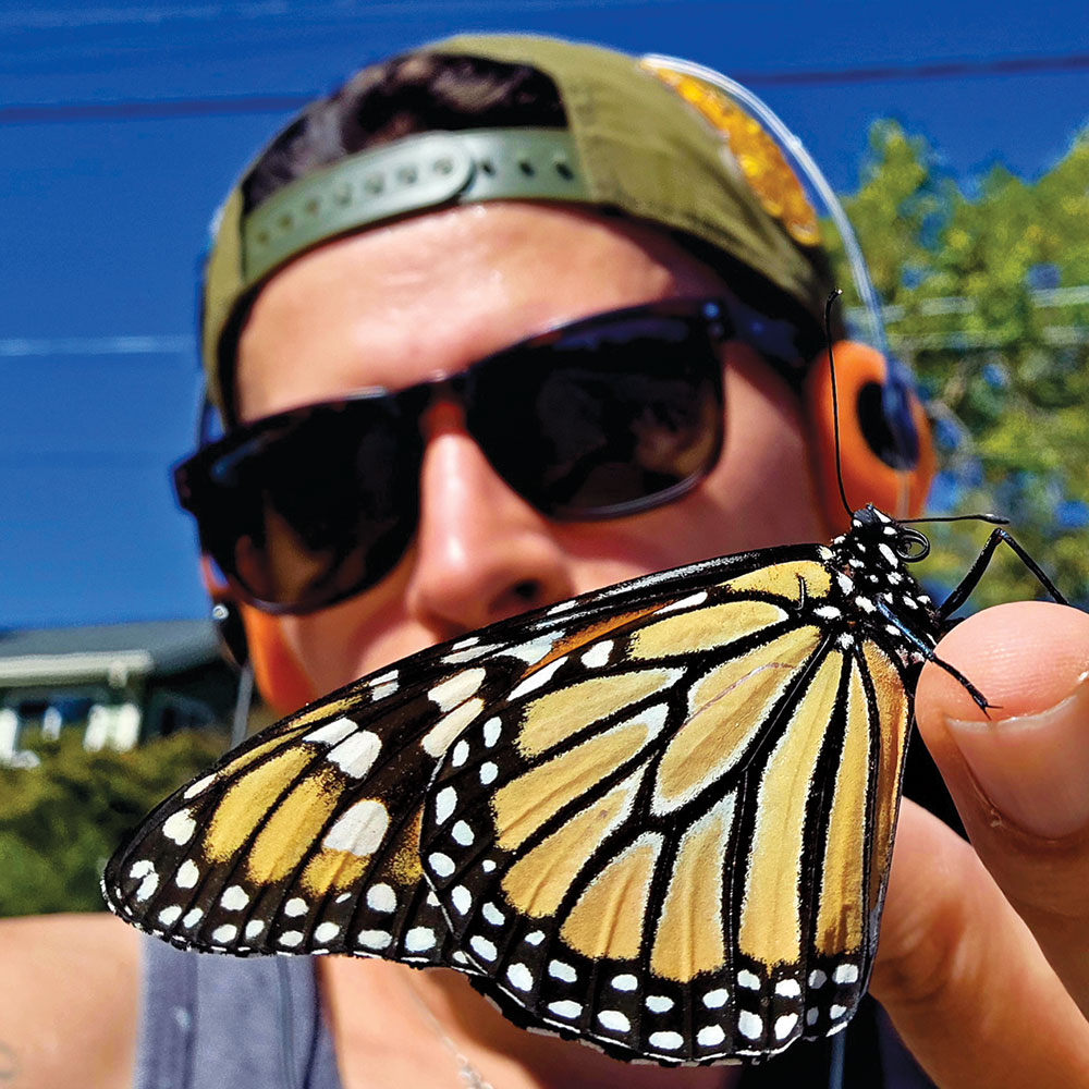 photo contest winner depicts a man in sunglasses holding a monarch butterfly