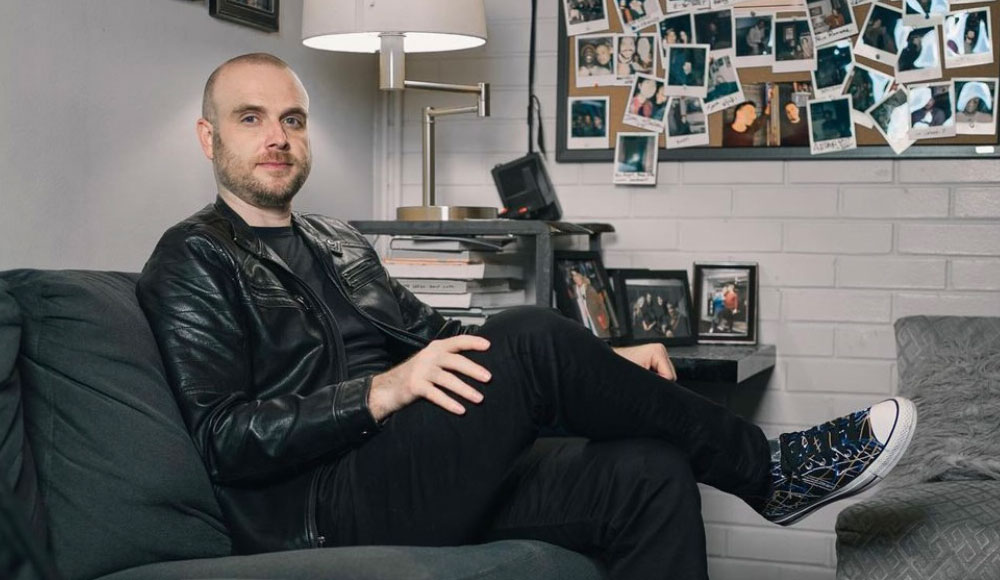 Man sitting on a couch next to a lamp and a painting