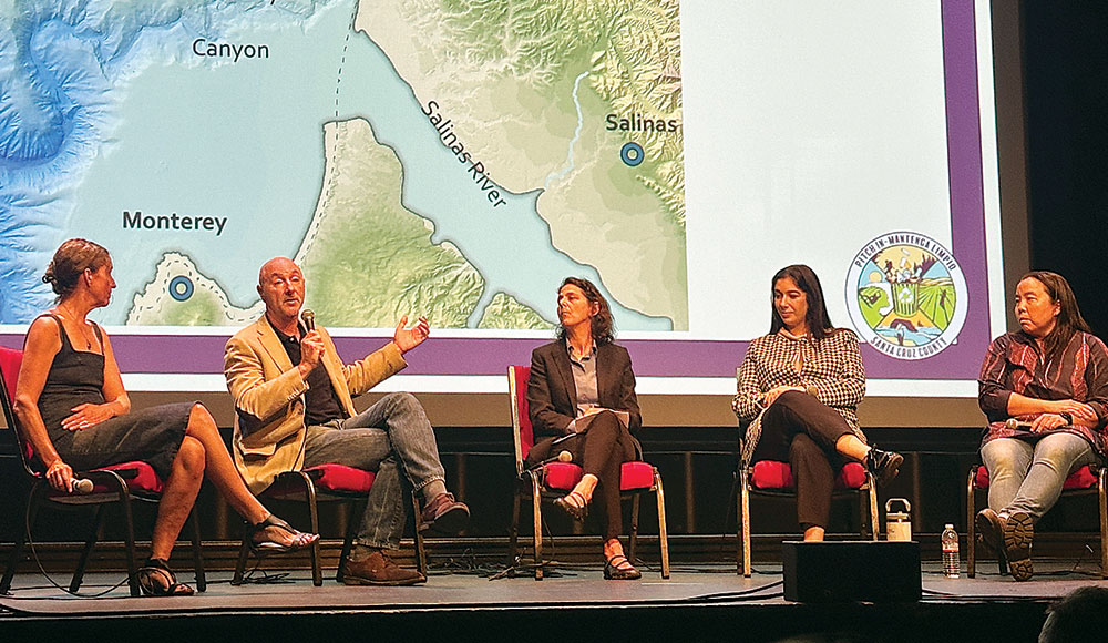 Panel of five speakers discussing ocean pollution at the Rio Theatre in Santa Cruz, seated before a map of Monterey Bay and the Salinas River.