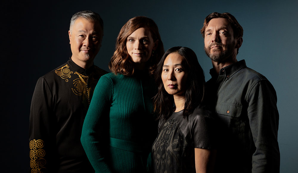 Members of the Del Sol Quartet pose together against a dark blue background.