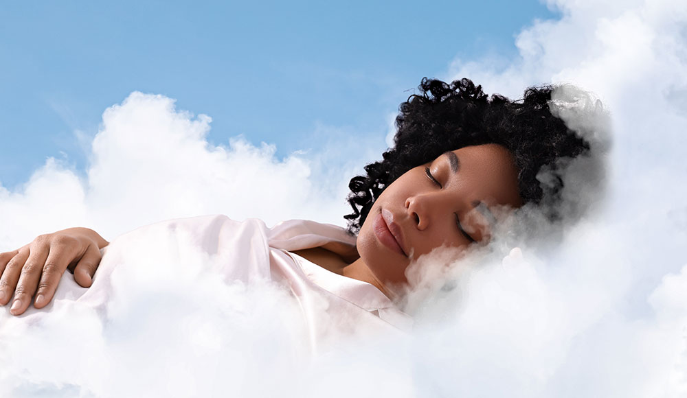 Woman peacefully sleeping on soft white clouds beneath a clear blue sky.