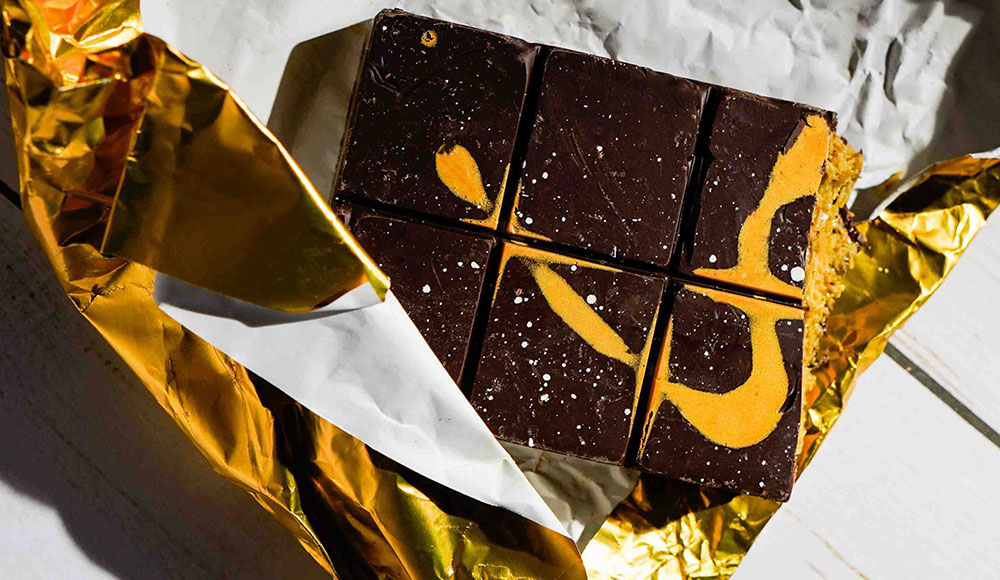 Dark chocolate Dubai bar from Spontaneous Confections, partially unwrapped in gold foil.