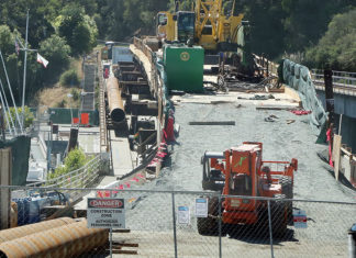 Bridge Still Out Construction equipment and materials sit atop the closed Murray Street Bridge in Santa Cruz, with fencing and warning signs blocking access.